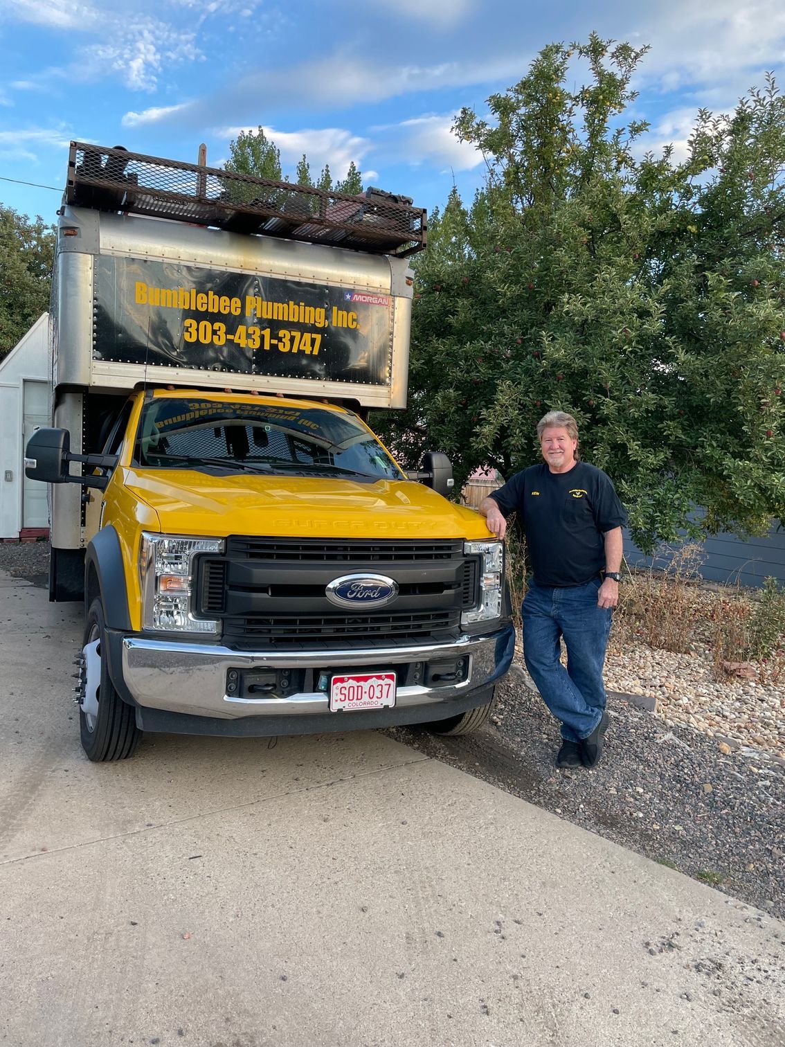 A man is standing in front of a yellow truck.