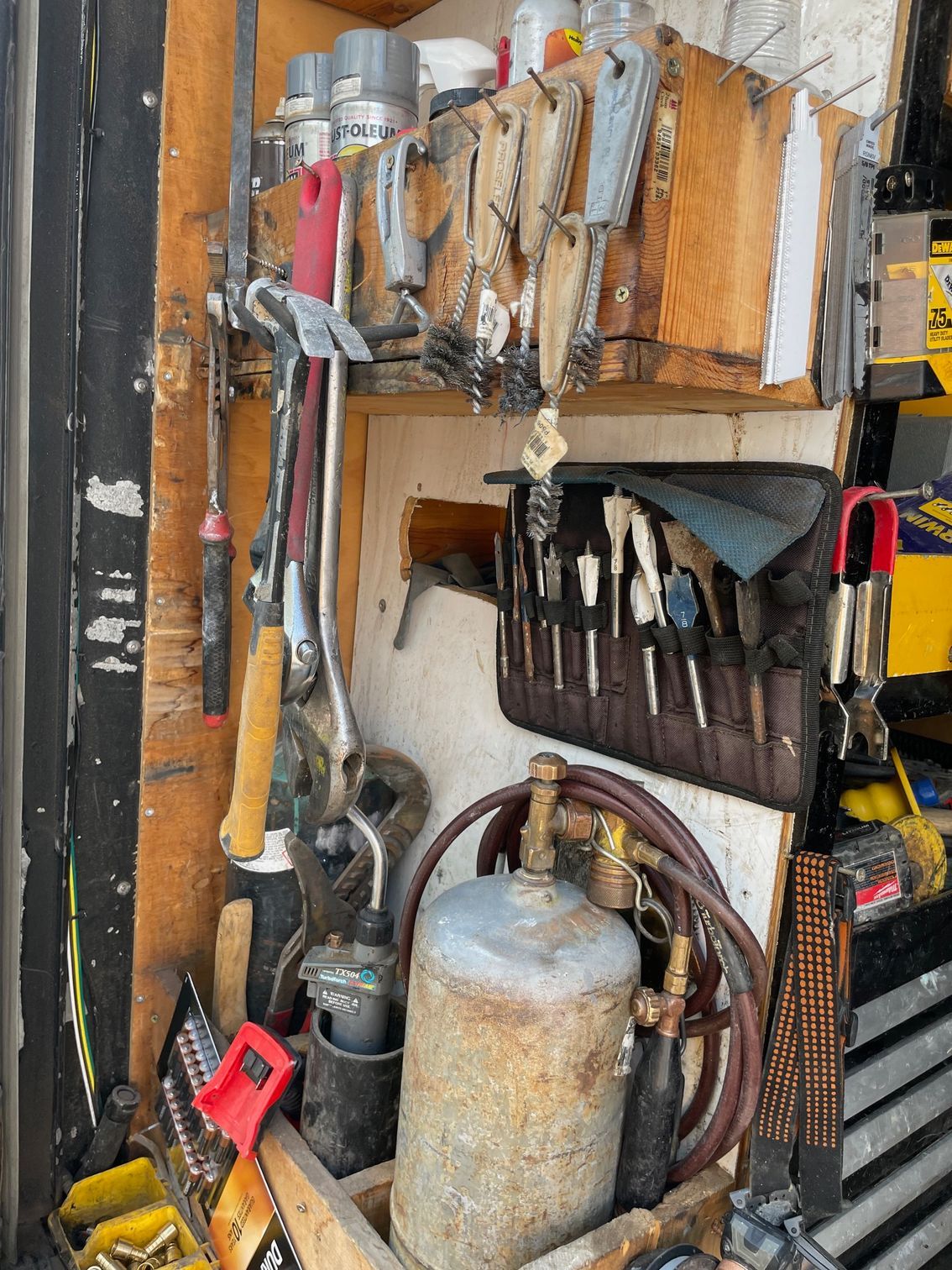 A bunch of tools are hanging on a wall in a garage.