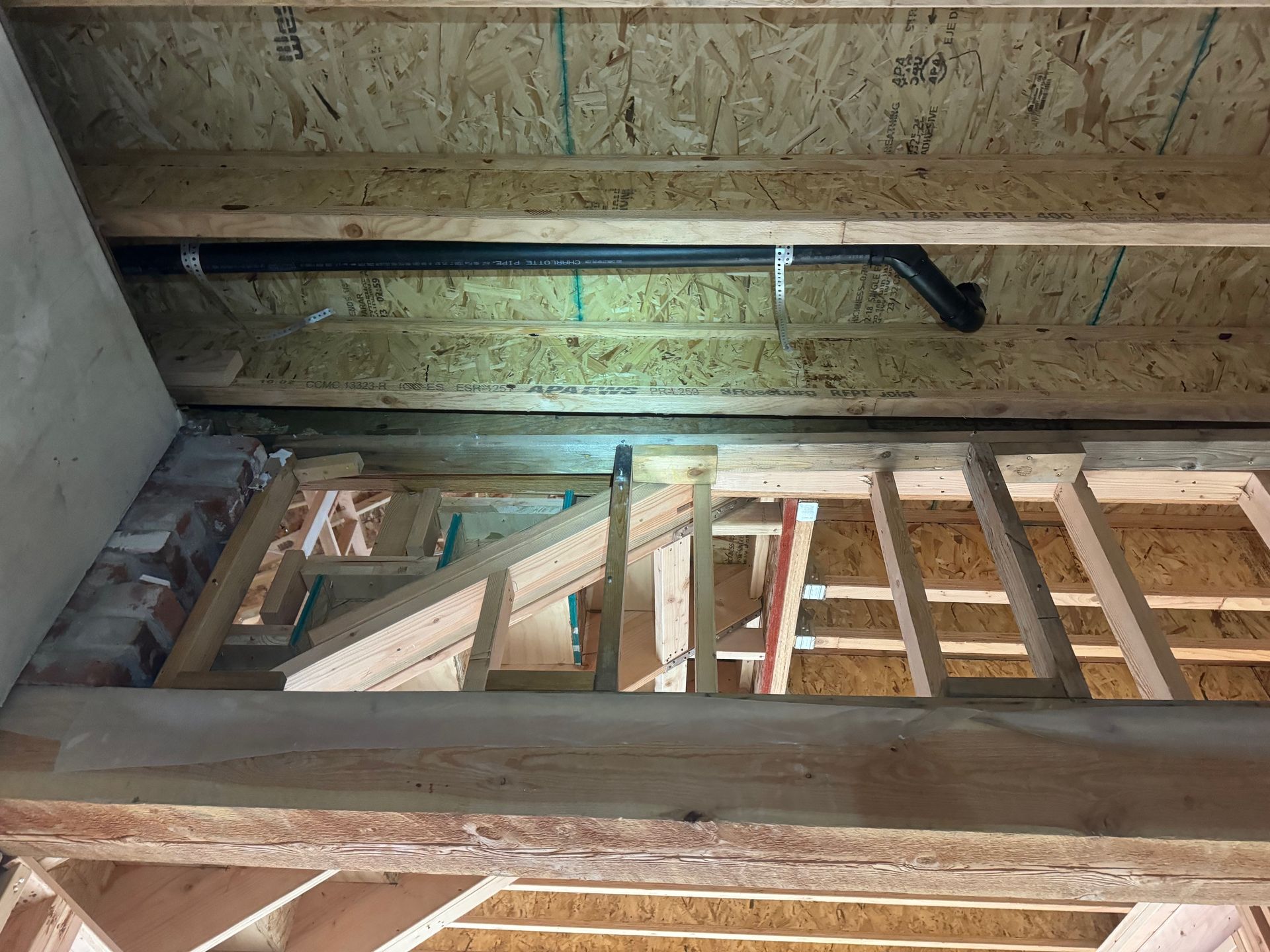 A ladder is hanging from the ceiling of a building under construction.