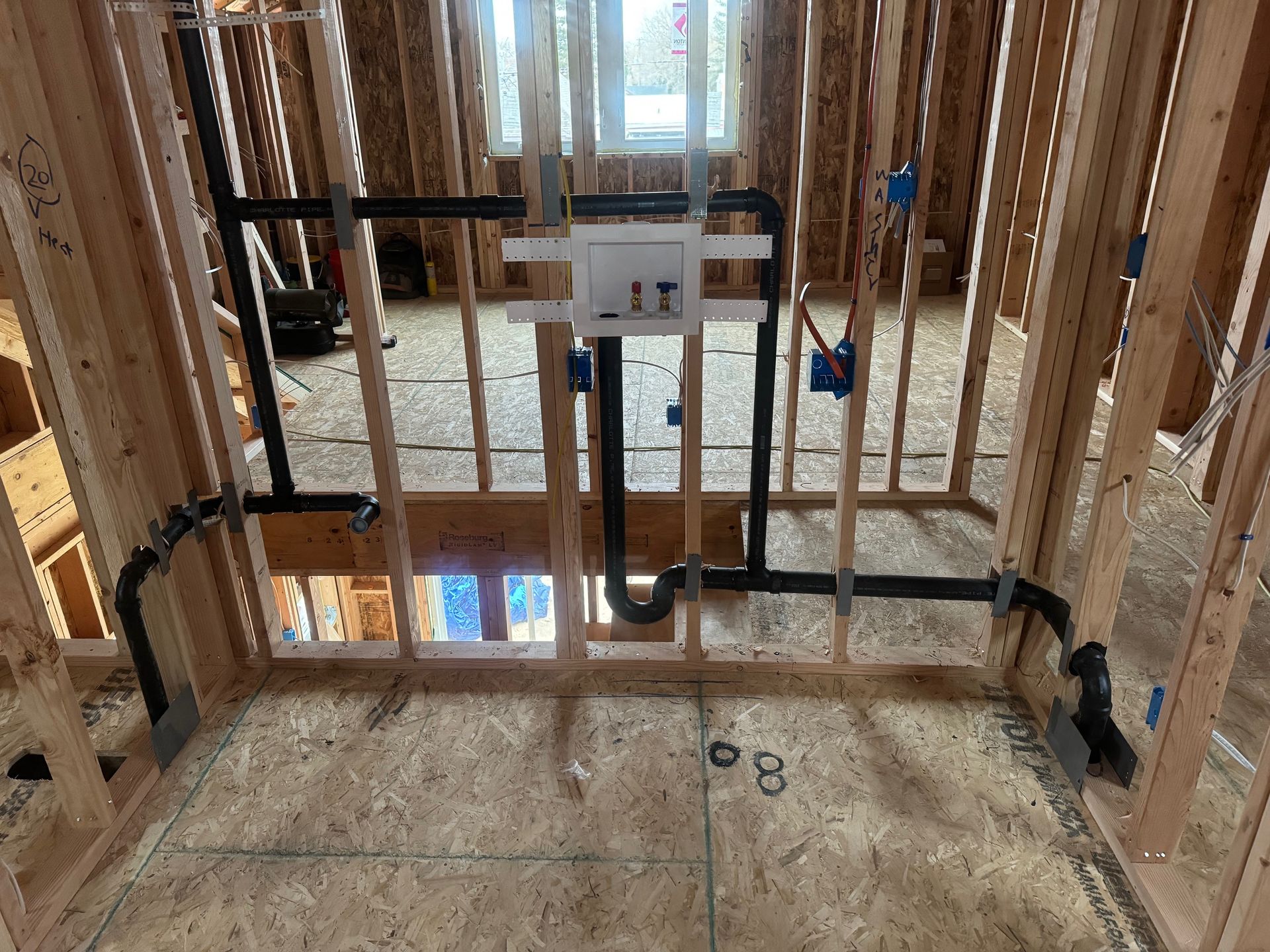 A room in a house under construction with pipes going through it.