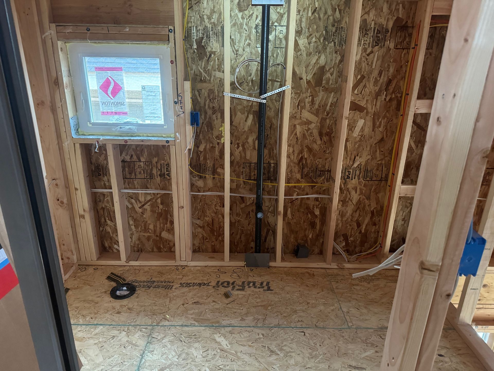 A room with a window and a pipe in it is being built.