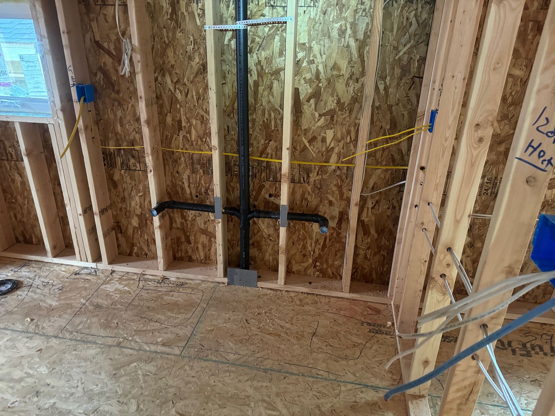 A pipe is being installed in the wall of a house under construction.