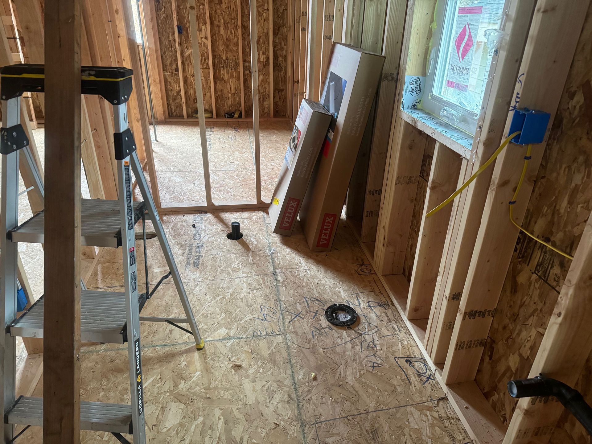 A ladder is sitting in the middle of a room in a house under construction.