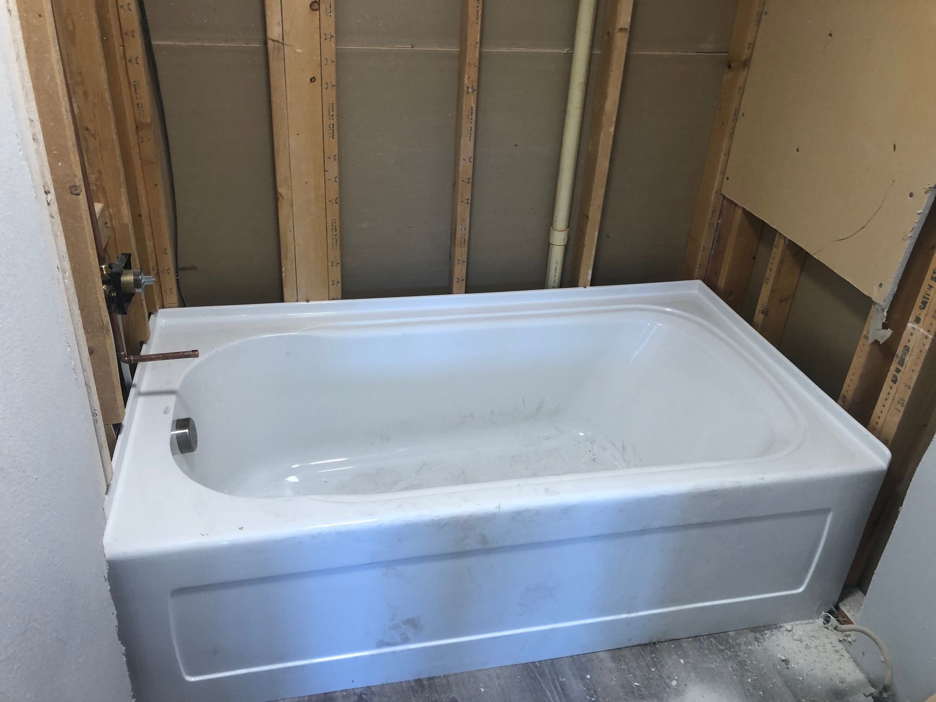 A white bathtub is sitting in a bathroom under construction.