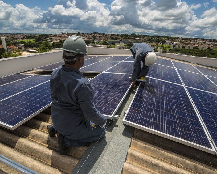 Two Workers Installing Solar Panels On The Roof Of A Building — Efficient Solar Panels in Armidale