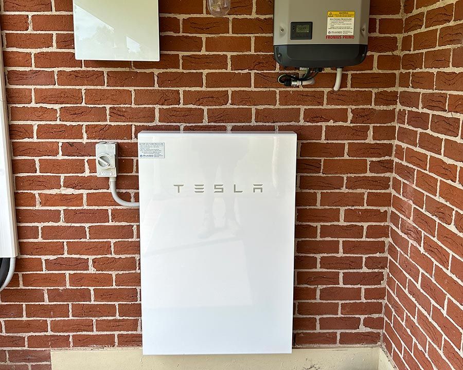 A Tesla Powerwall Is Mounted On A Brick Wall — Experienced Solar Installers in Tamworth