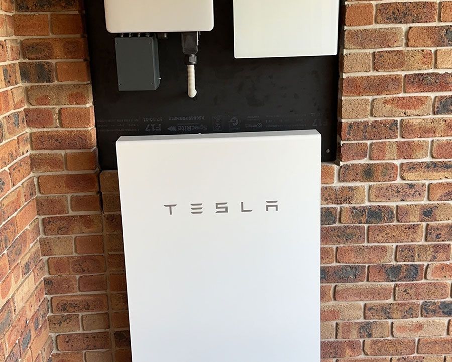 A Tesla Powerwall Is Mounted On A Brick Wall — Experienced Solar Installers in Tamworth