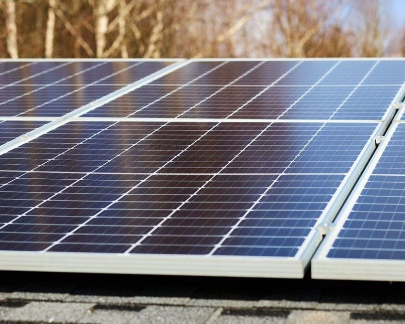 A Row Of Solar Panels On A Roof With Trees In The Background — Efficient Solar Panels in Armidale