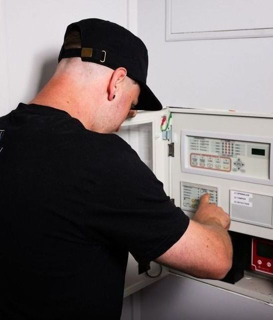 Man Fixing Control Panel of Fire Alarms