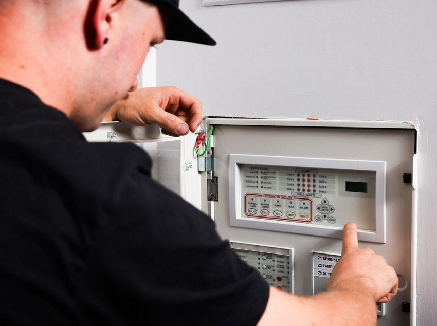 Man Fixing Control Panel of Fire Alarms