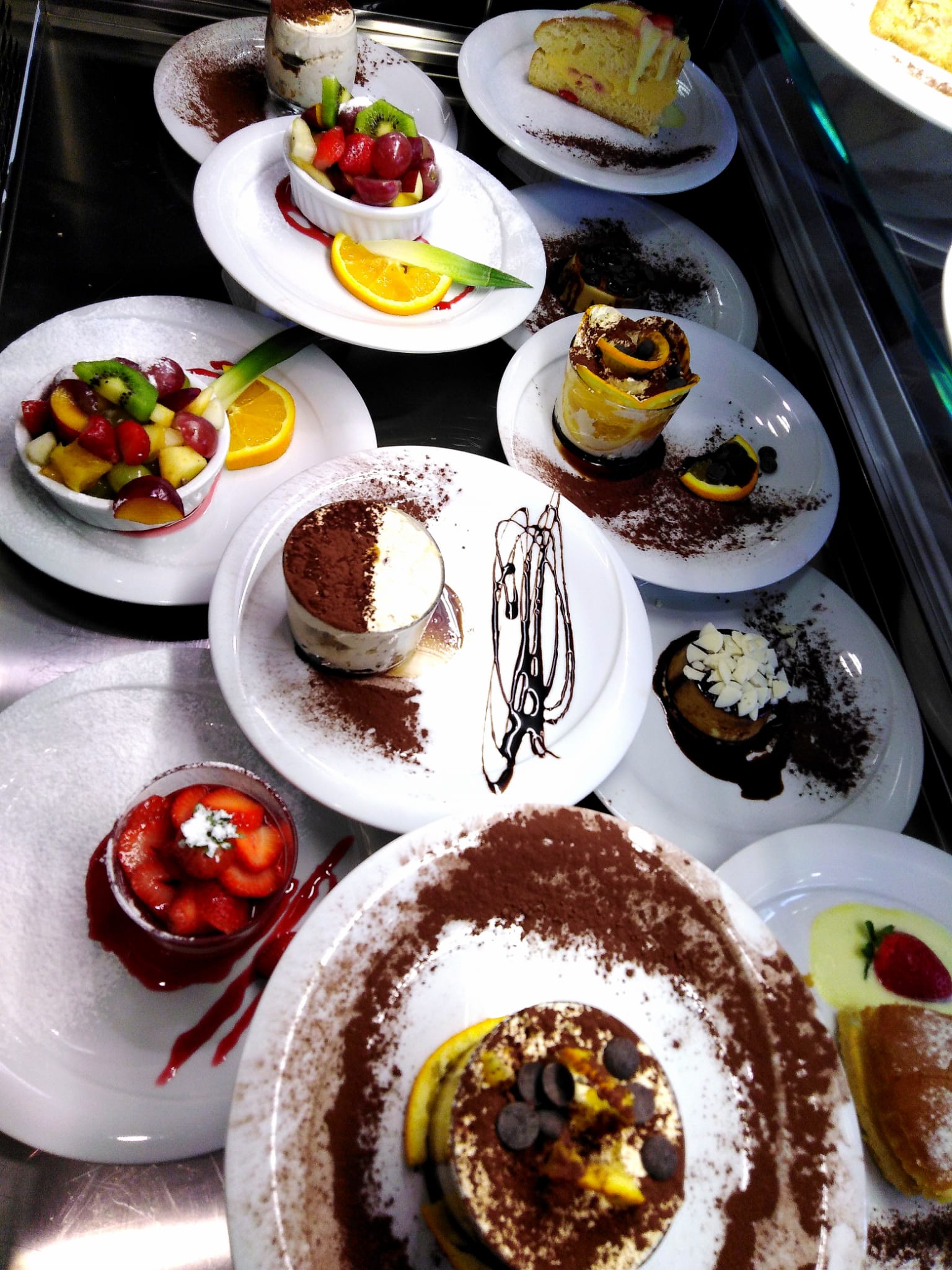 Una varietà di dessert sono esposti su piatti bianchi