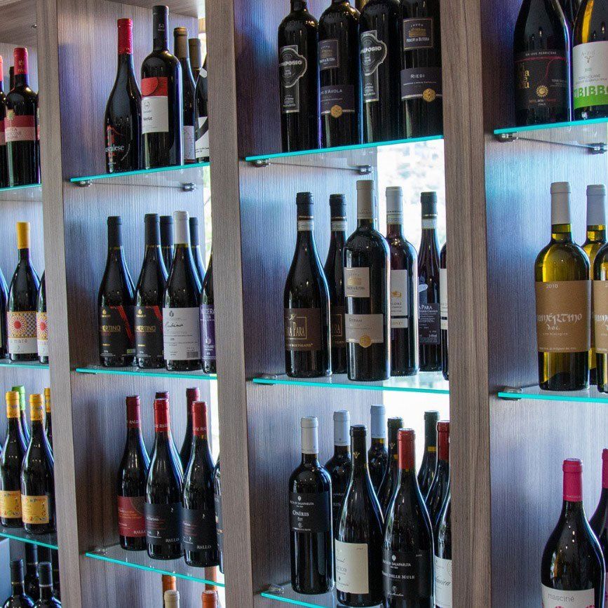 Uno scaffale pieno di bottiglie di vino, tra cui una bottiglia con la scritta