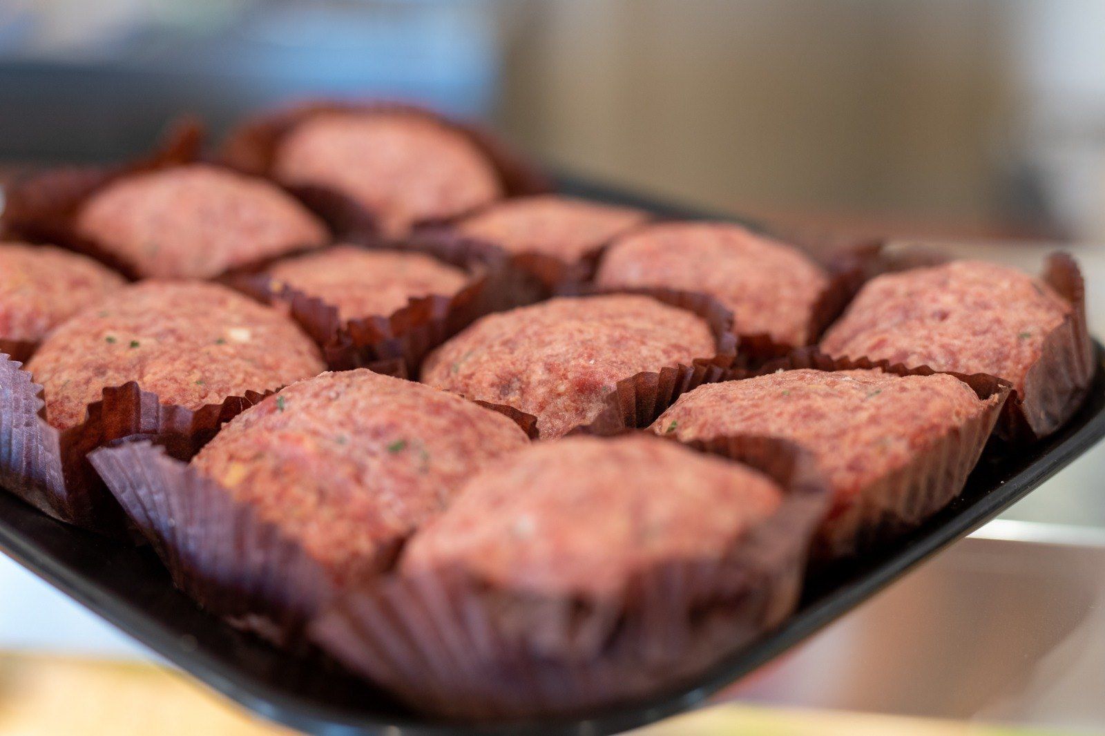 Un vassoio nero pieno di cupcakes rossi su un tavolo.