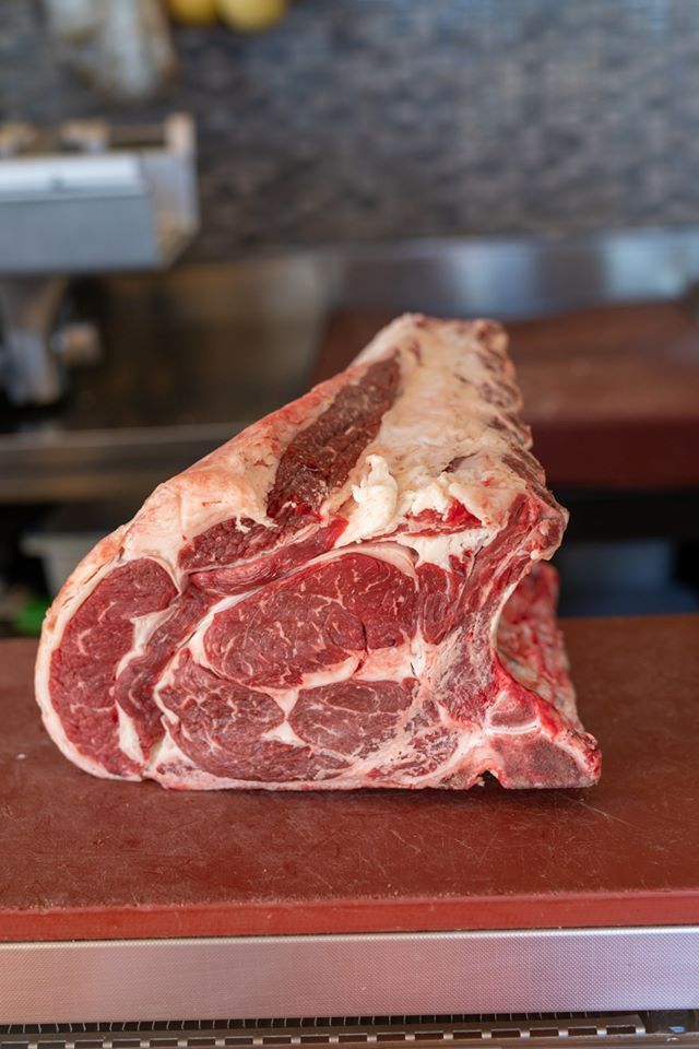 Un grosso pezzo di carne cruda è appoggiato su un tagliere.