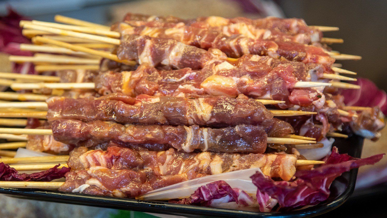 Una pila di spiedini di carne disposti uno sopra l'altro su un piatto.