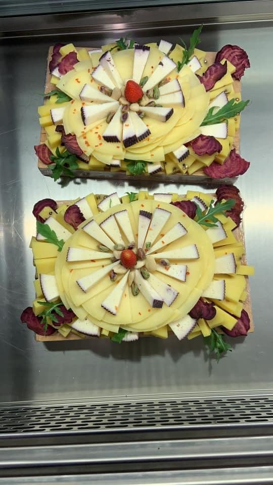 Due vassoi di formaggio e carne sono appoggiati su un vassoio di acciaio inossidabile.