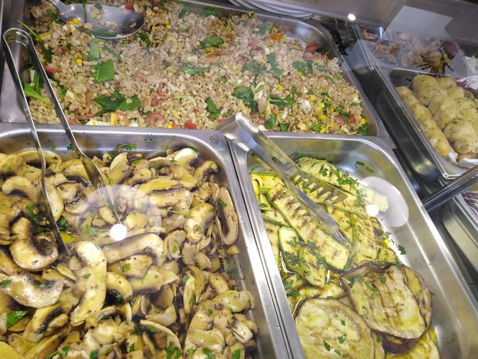 Un buffet con una varietà di cibi tra cui riso, funghi, zucchine e melanzane.