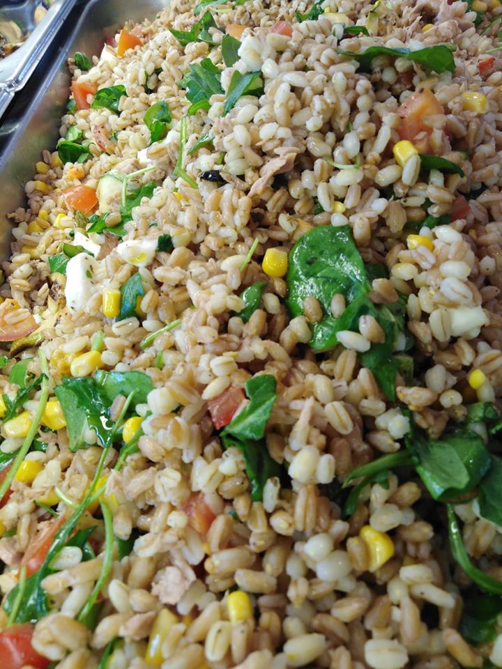 Primo piano di un'insalata con riso e verdure su un vassoio.