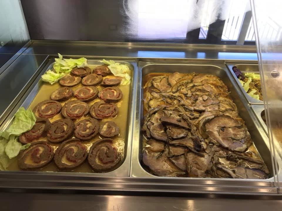 Due vassoi di cibo sono appoggiati sul bancone di un ristorante.