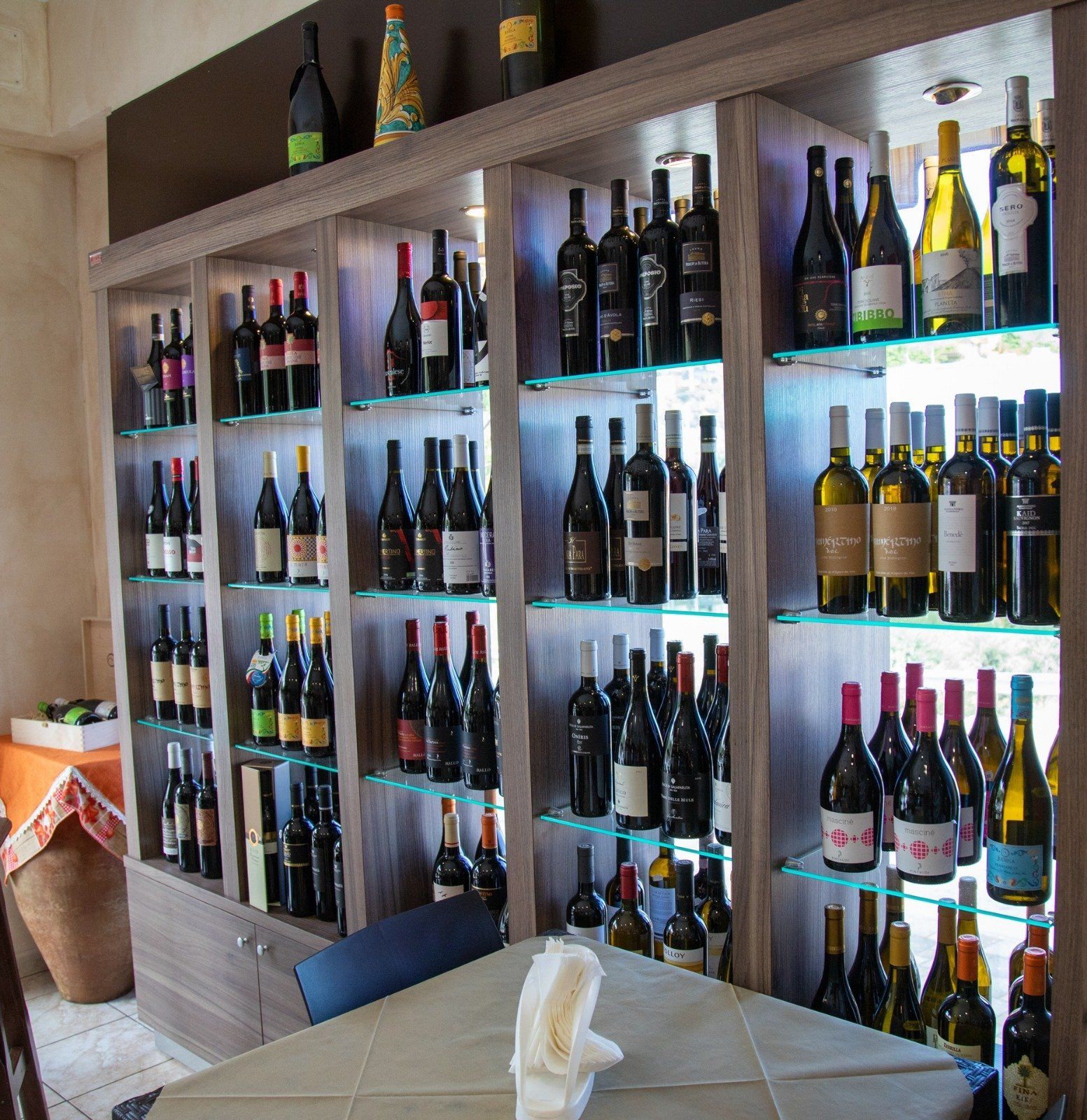 Uno scaffale pieno di bottiglie di vino tra cui una bottiglia di vino con etichetta bianca