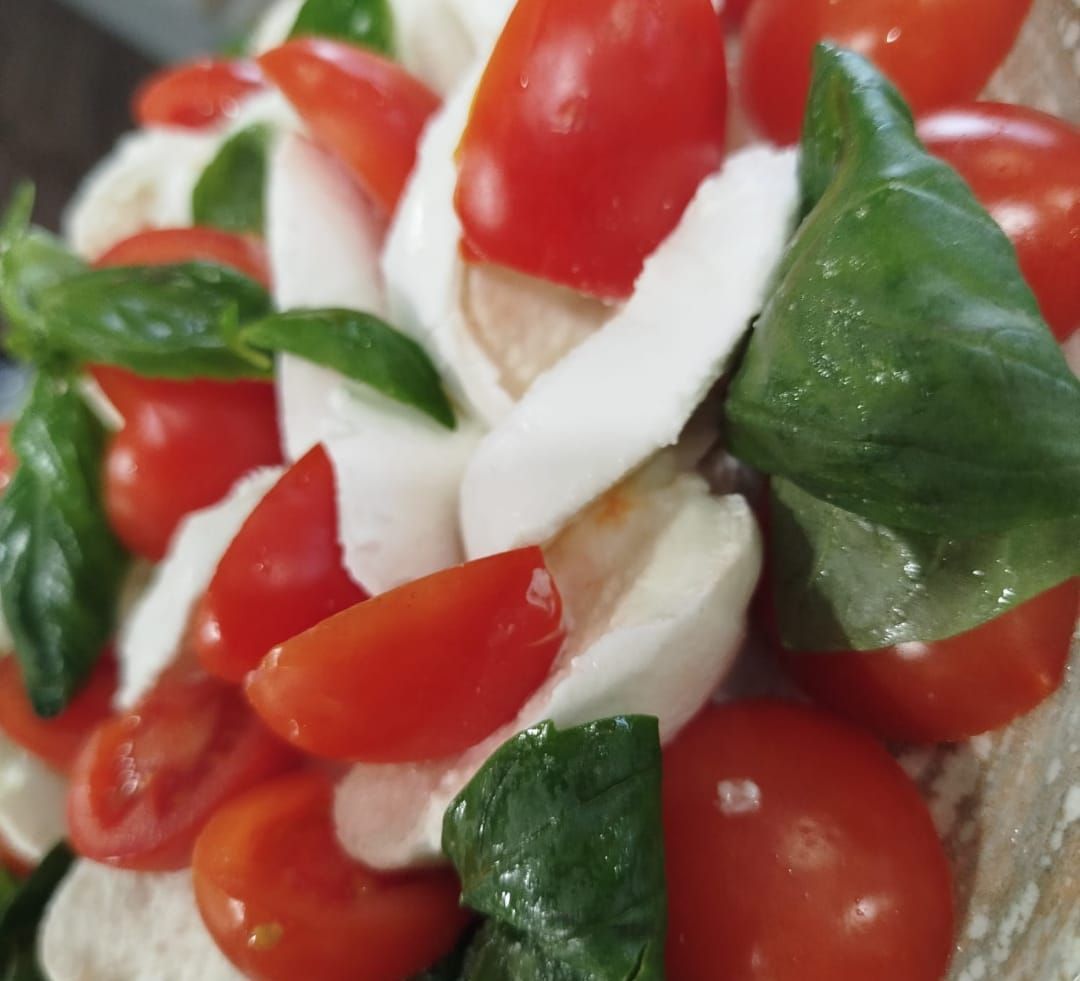 Un primo piano di un'insalata con pomodori mozzarella e basilico