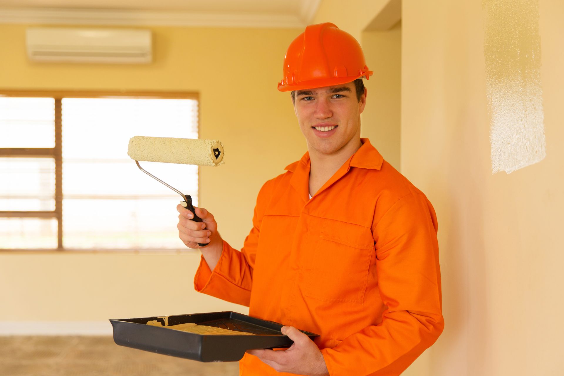 Interior painting contractor applying fresh paint with roller for home improvement project today.