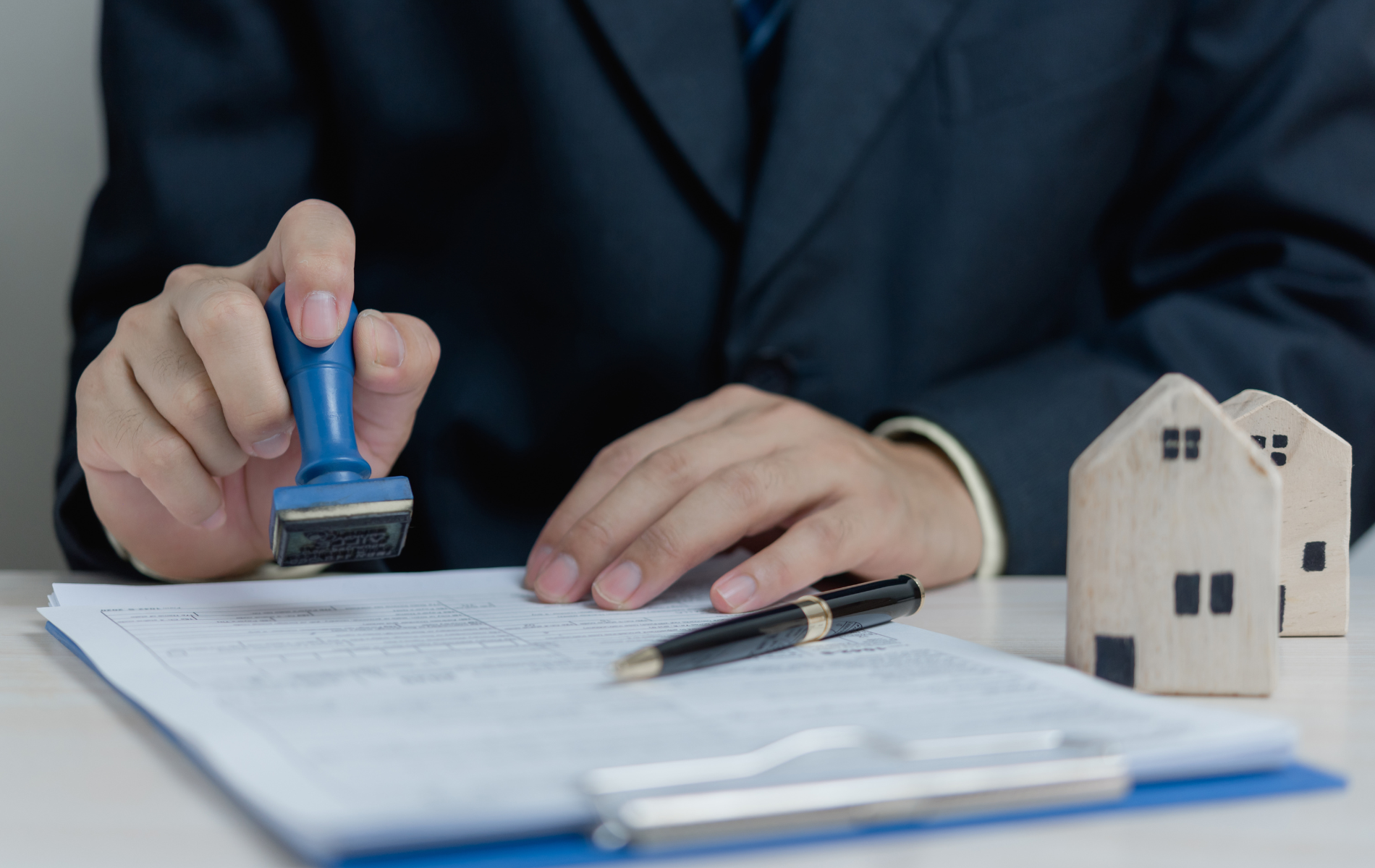 A man in a suit is stamping a document on a clipboard.