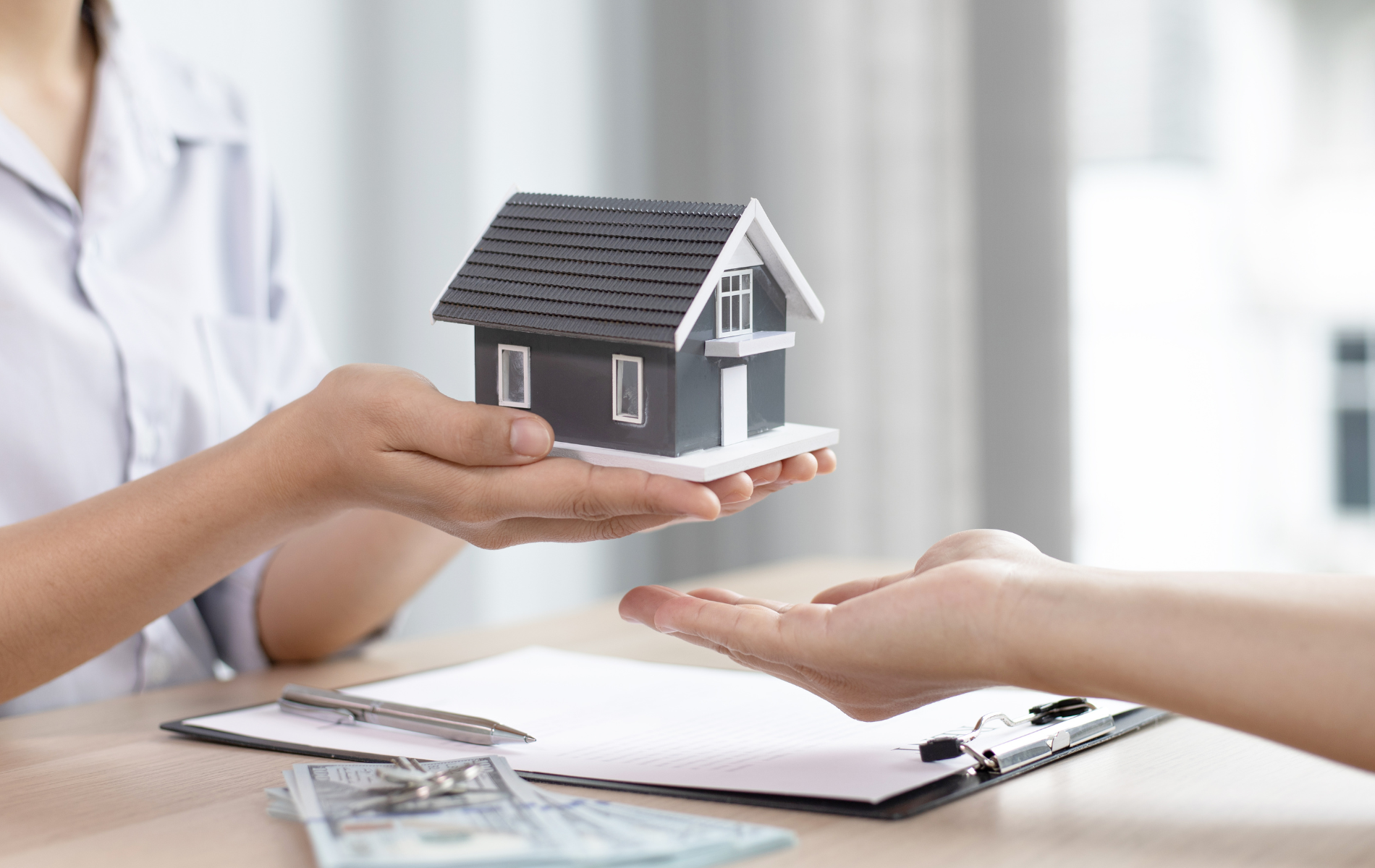 A woman is giving a model house to a man.