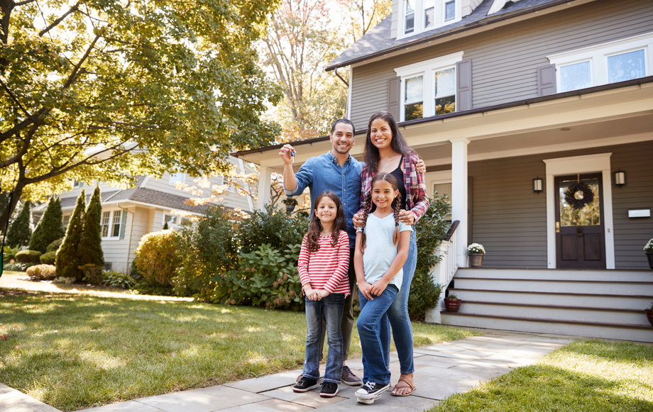 A family is standing in front of their new home.