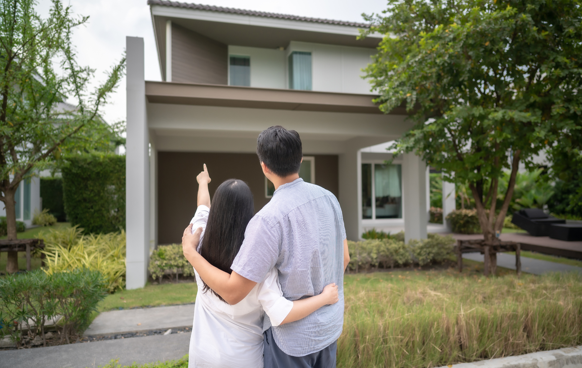 A man and a woman are standing in front of a house.
