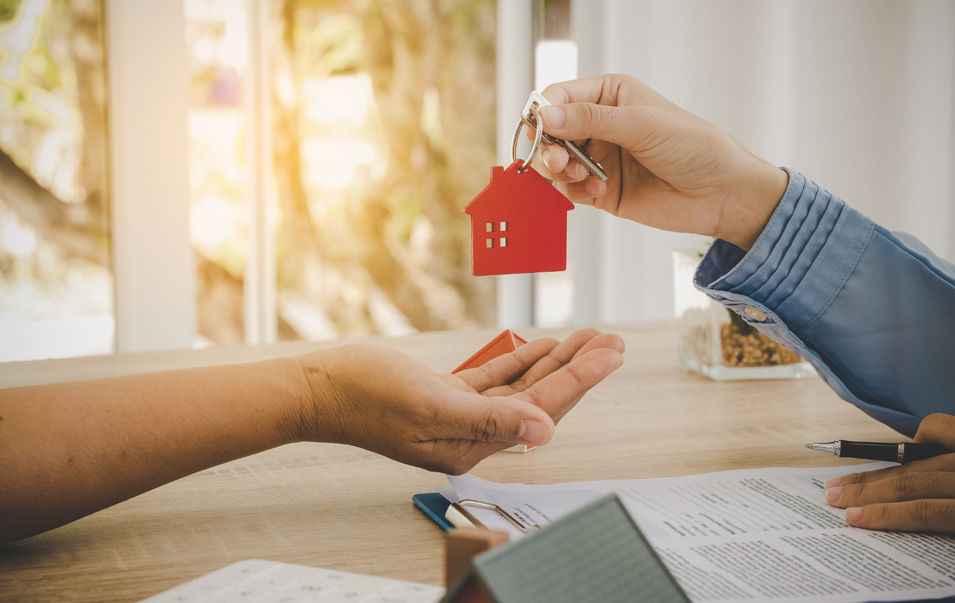 A person is handing a house key to another person.