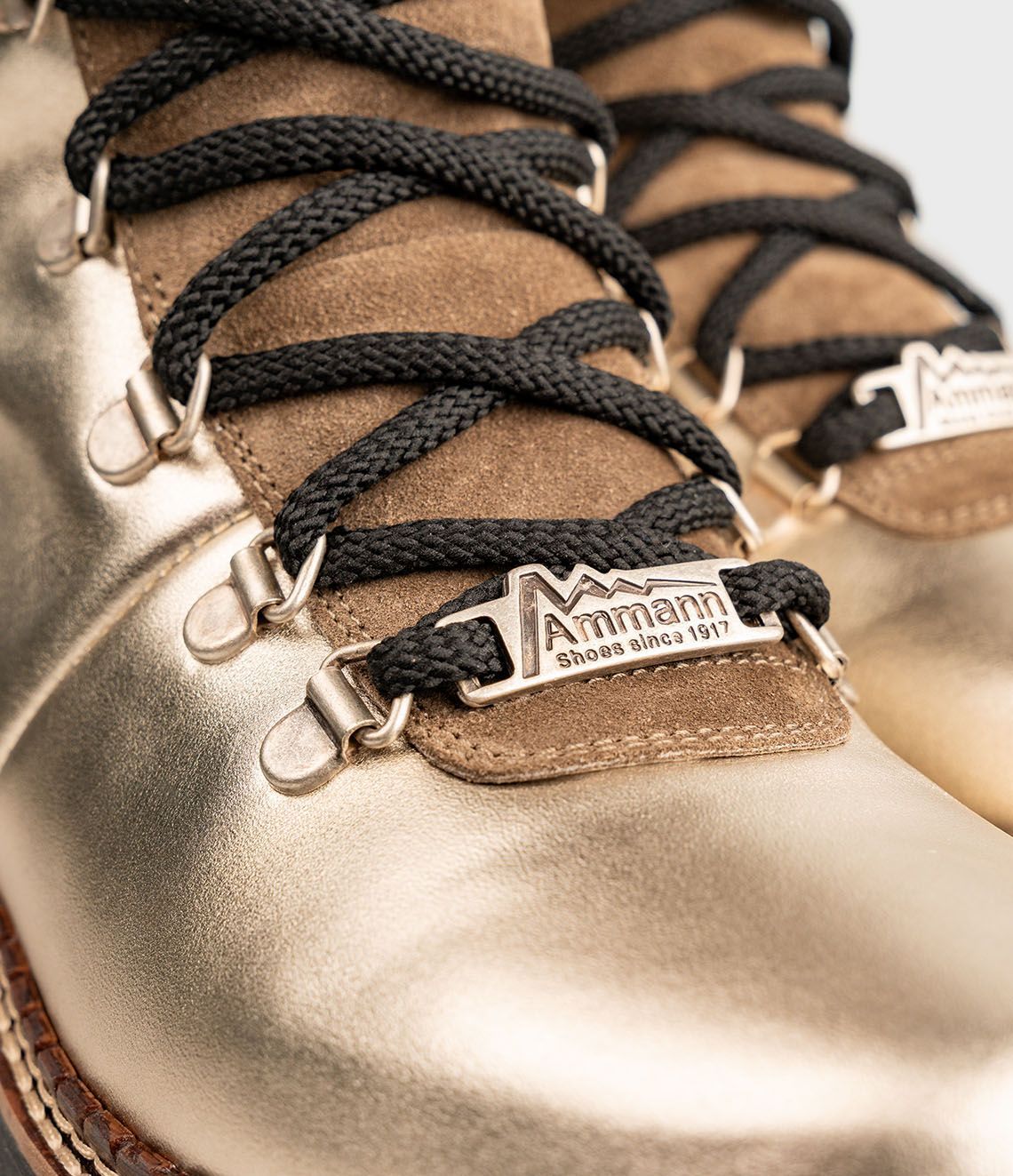 Bottes à lacets dorées et beiges avec revers roulés et lacets noirs.