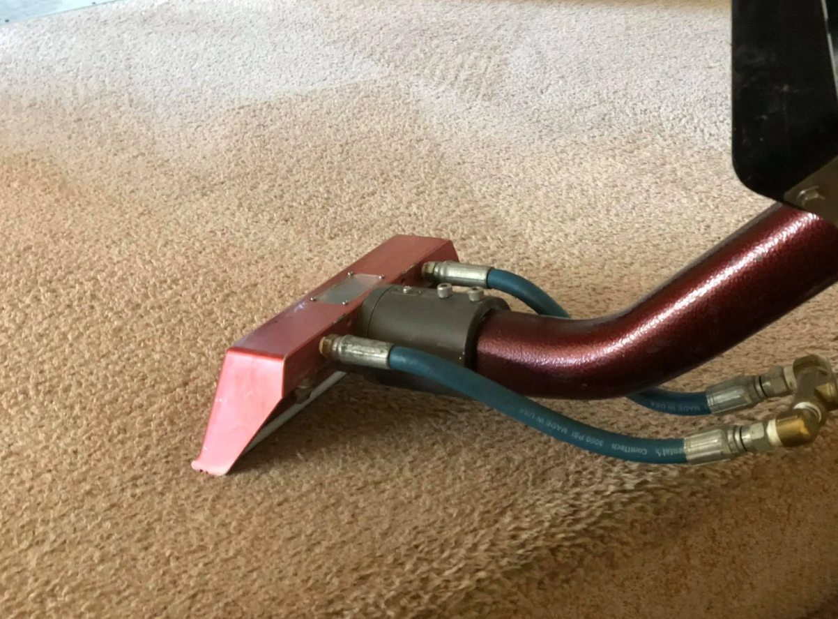 A vacuum cleaner is being used to clean a carpet.