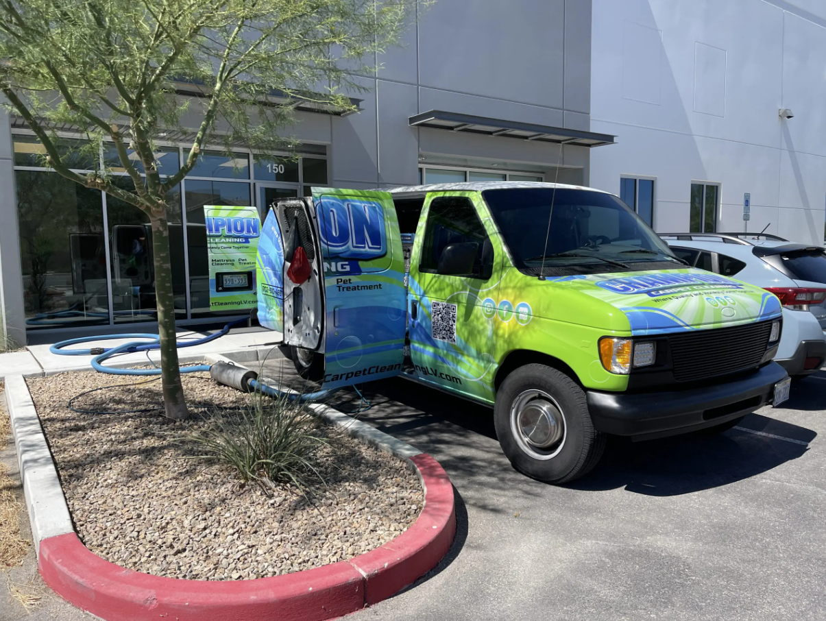 A green and blue van is parked in front of a building.