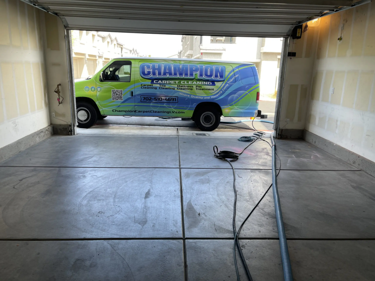 A green van is parked in a garage with the door open.