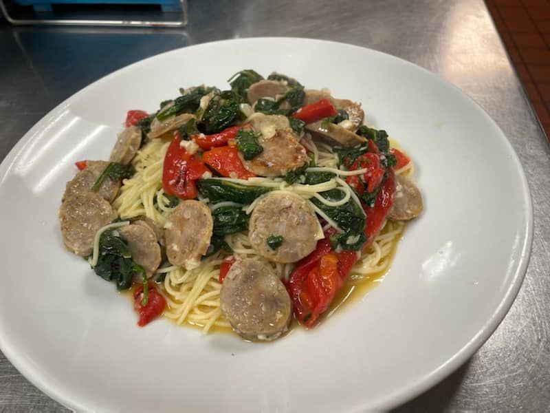 A white plate topped with spaghetti meatballs and peppers