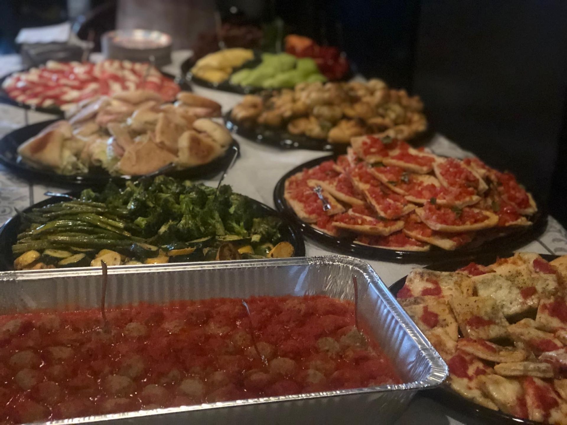 A table topped with plates of food including pizza and vegetables.