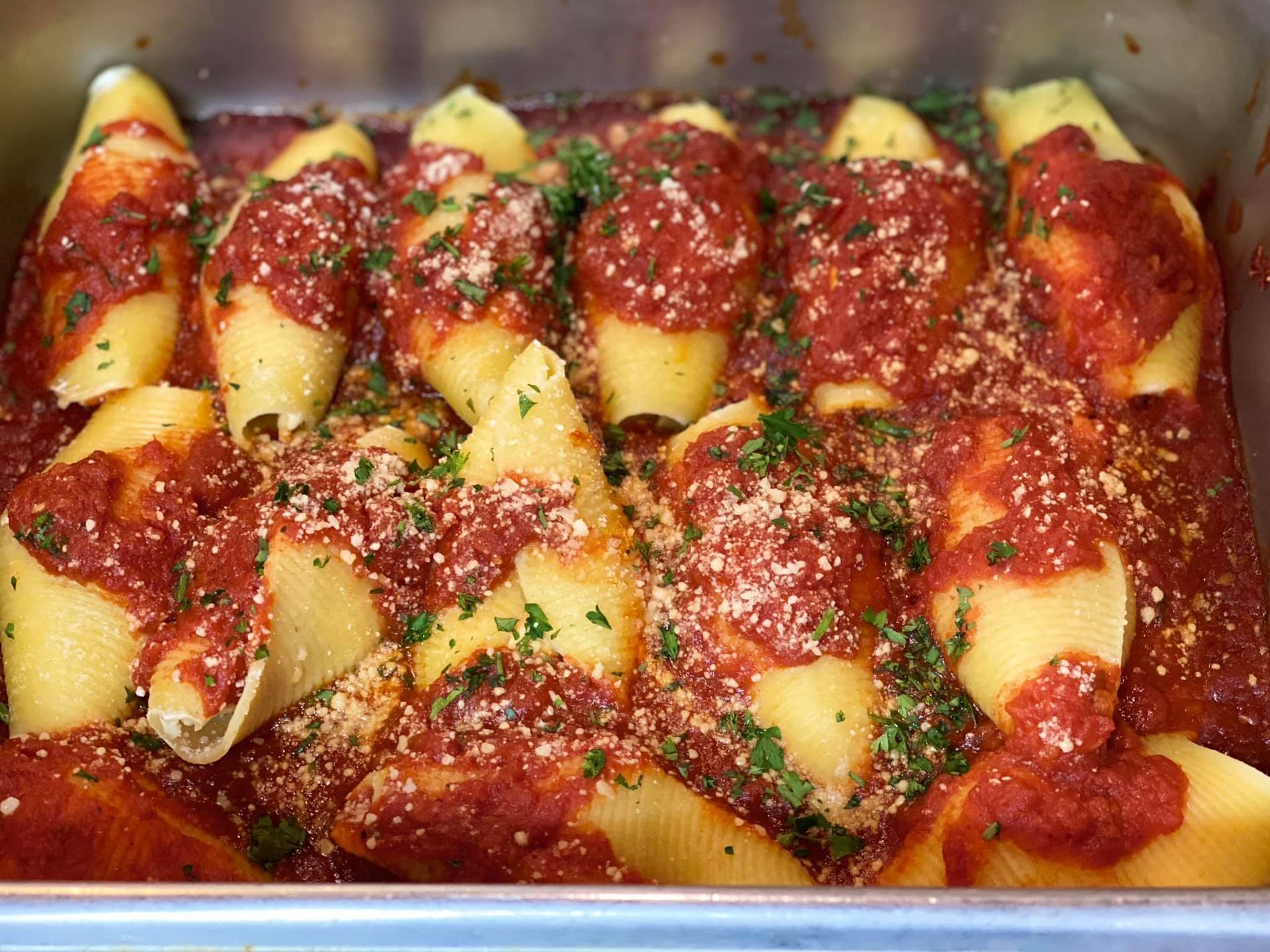 A casserole dish filled with stuffed shells and tomato sauce.