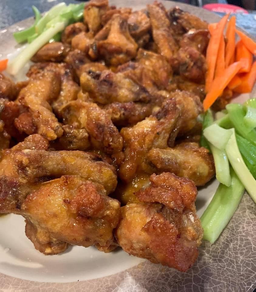 A plate of chicken wings with carrots and celery on a table.