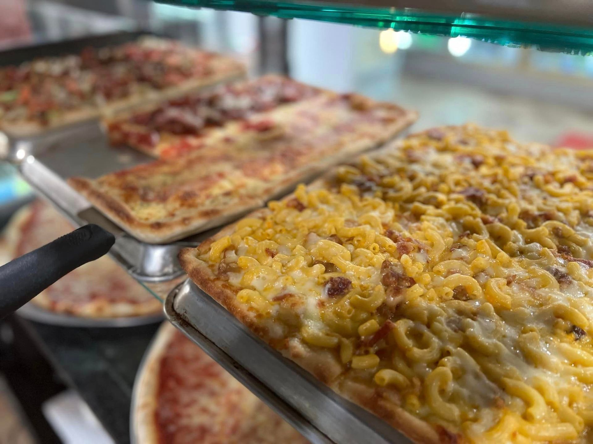 A tray of macaroni and cheese pizza is sitting on a table.