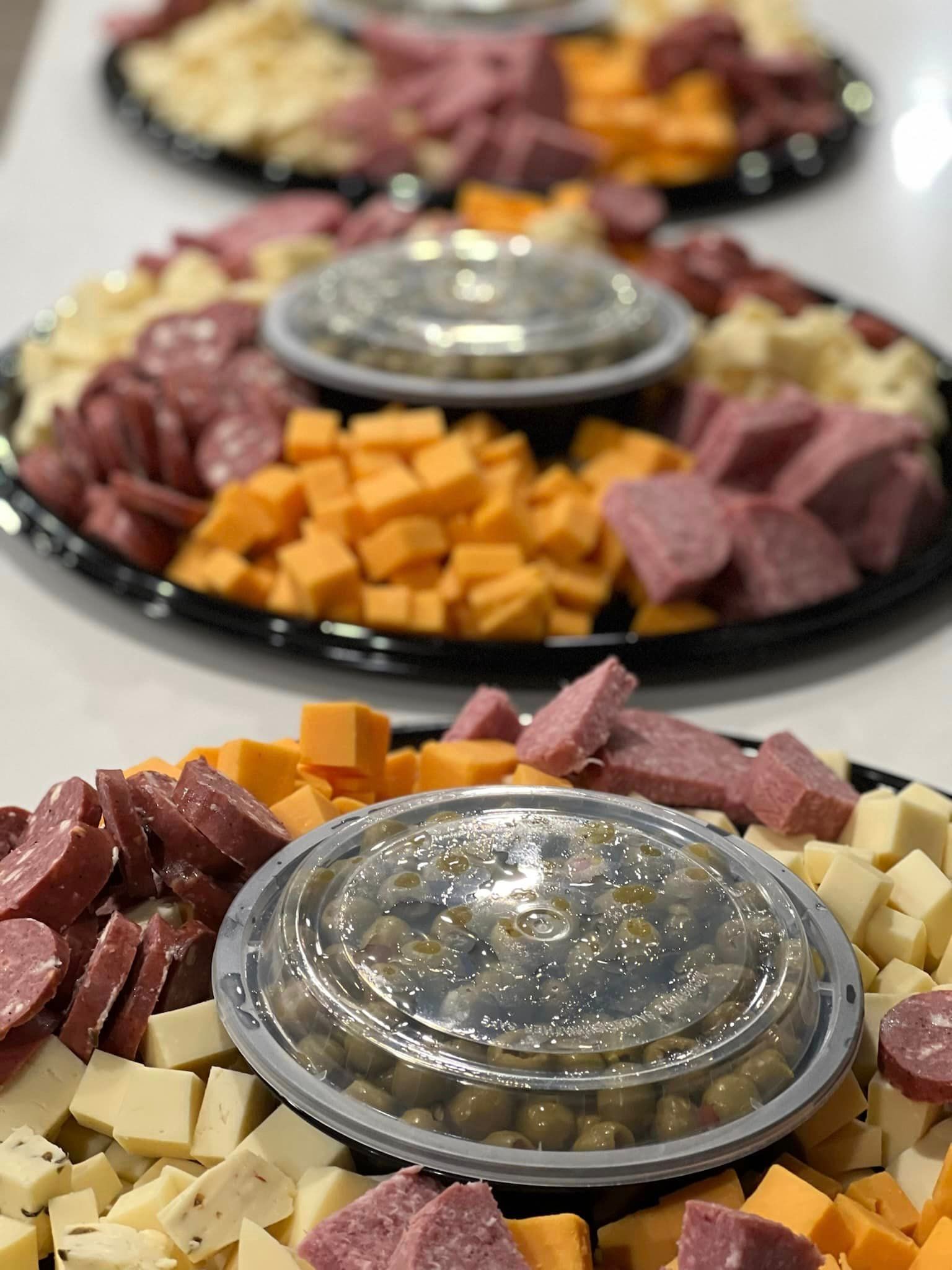 A tray of cheese , meat and olives on a table.