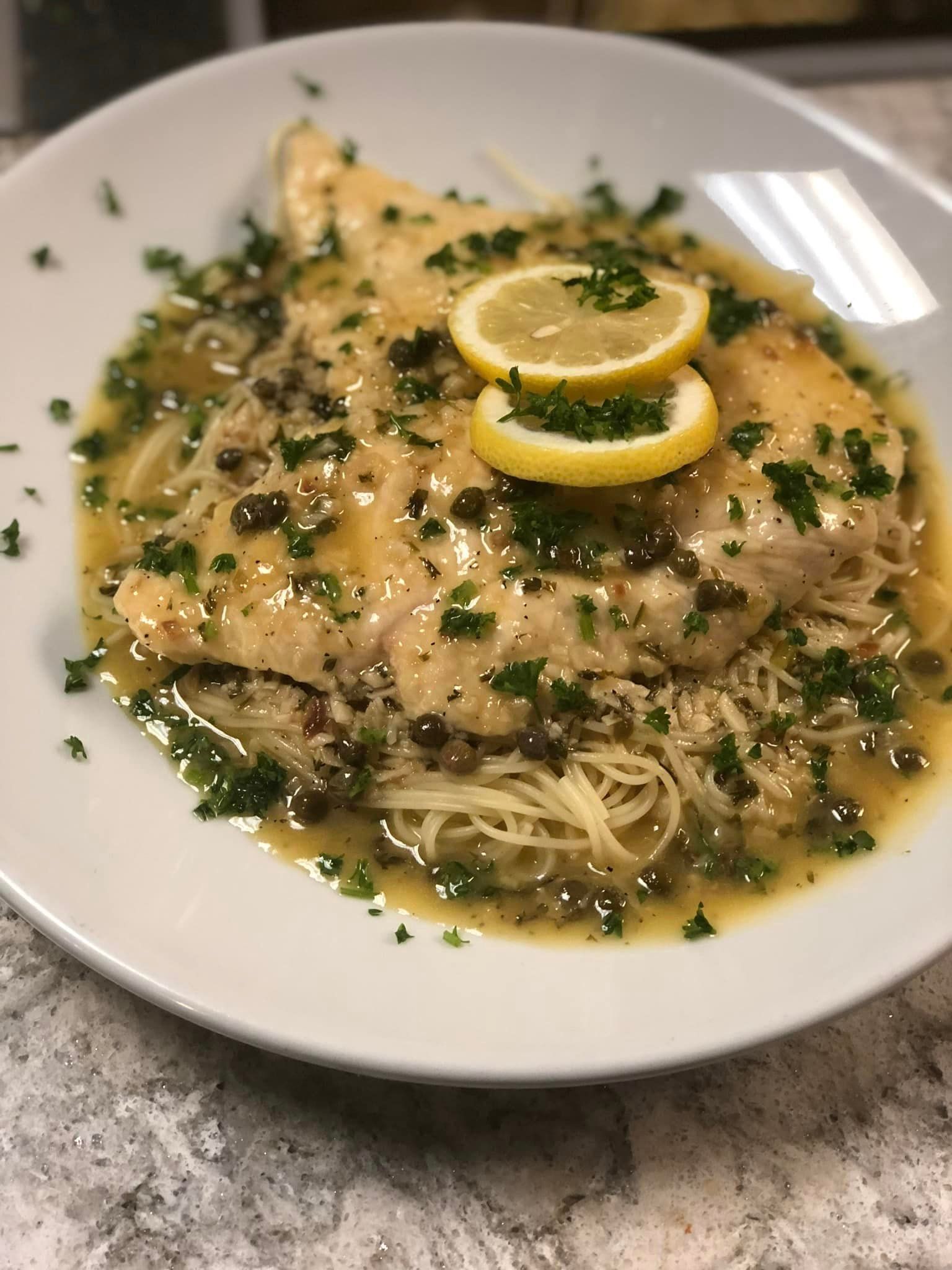 A plate of food with noodles and lemon slices on a table.