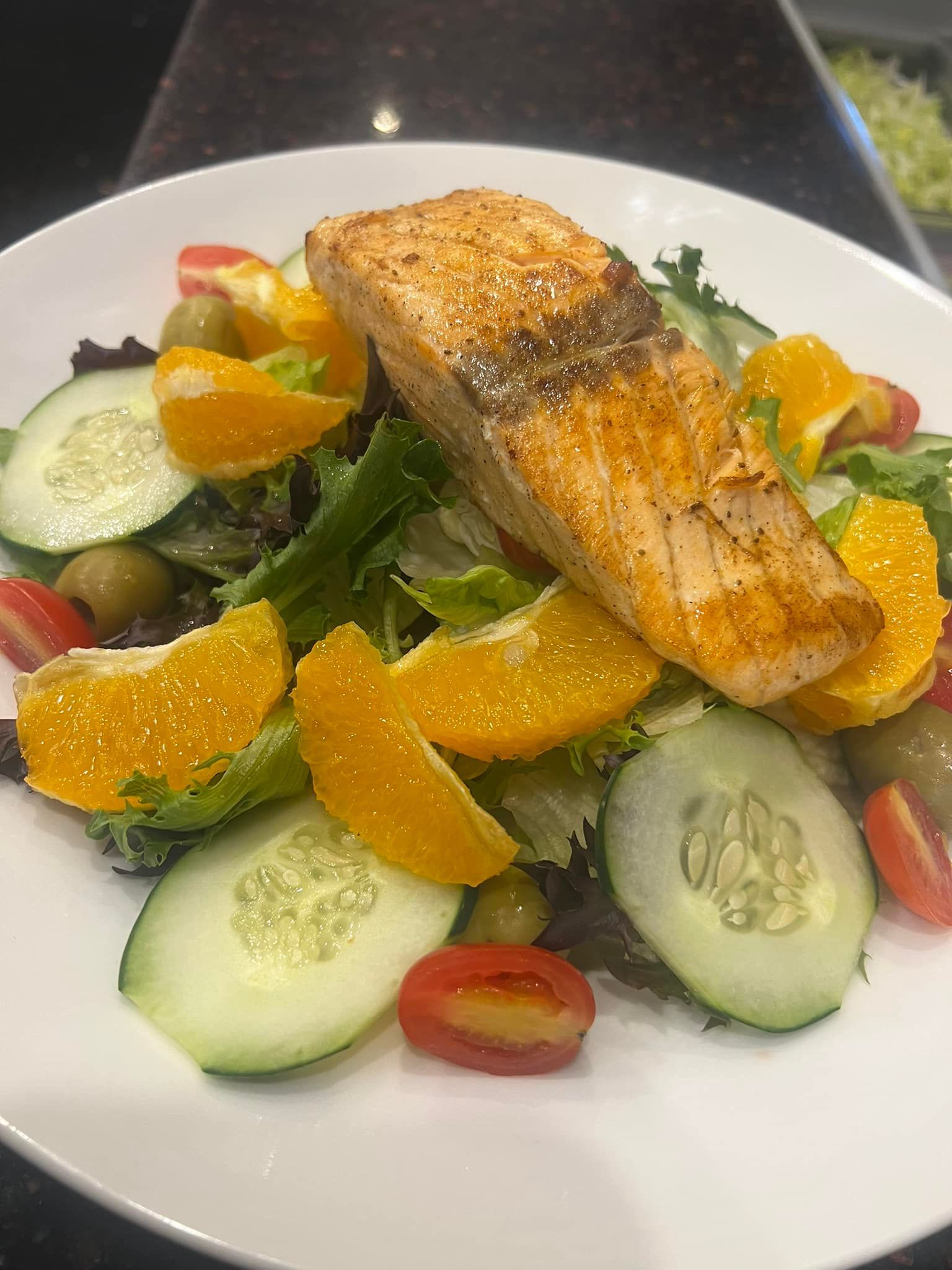 A white plate topped with a salad and a piece of salmon.