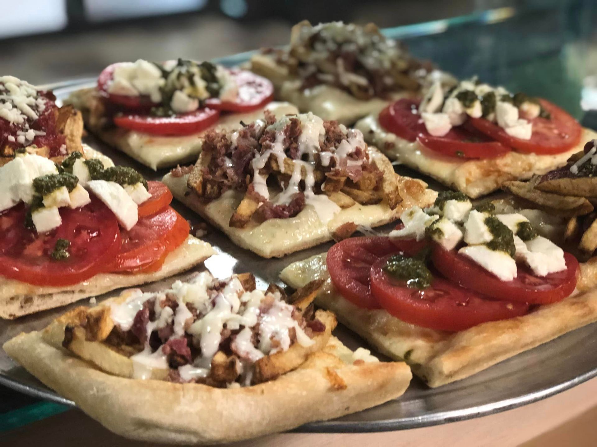 A tray of pizzas with tomatoes and cheese on them