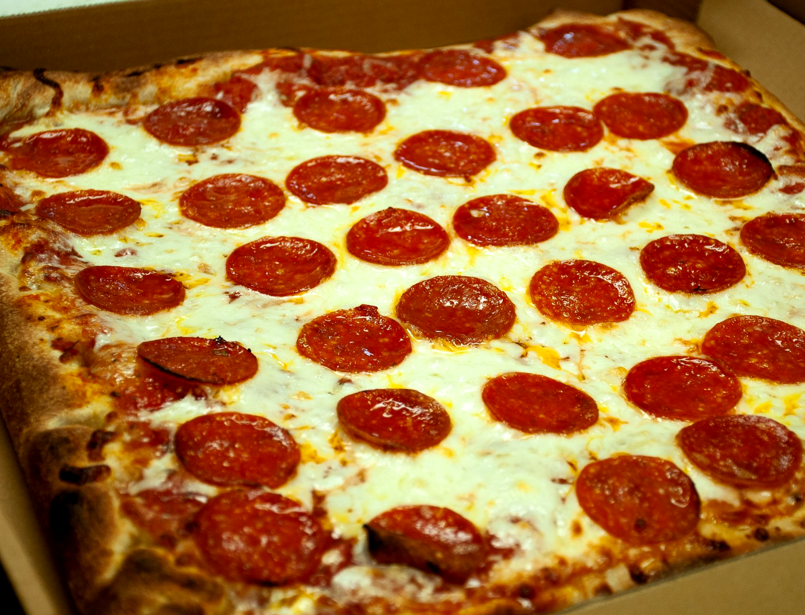 A pepperoni pizza is in a cardboard box.