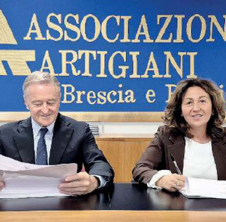 Due persone sedute a un tavolo firmano dei documenti. 