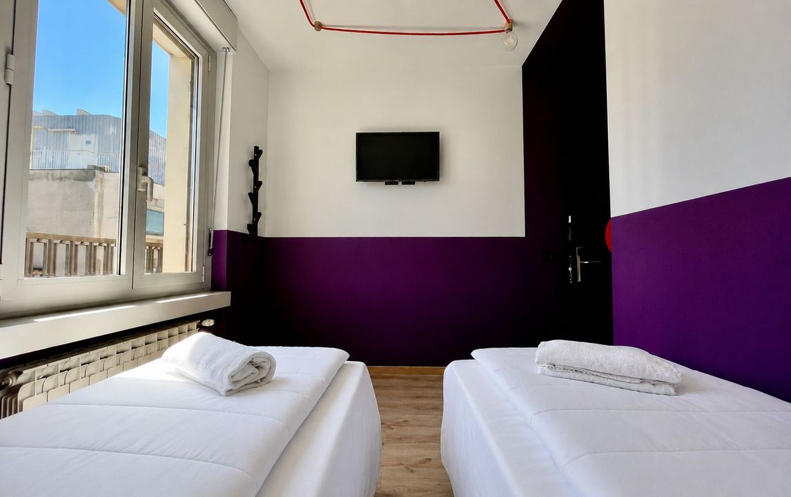 Una camera da letto con due letti e una televisione a parete.