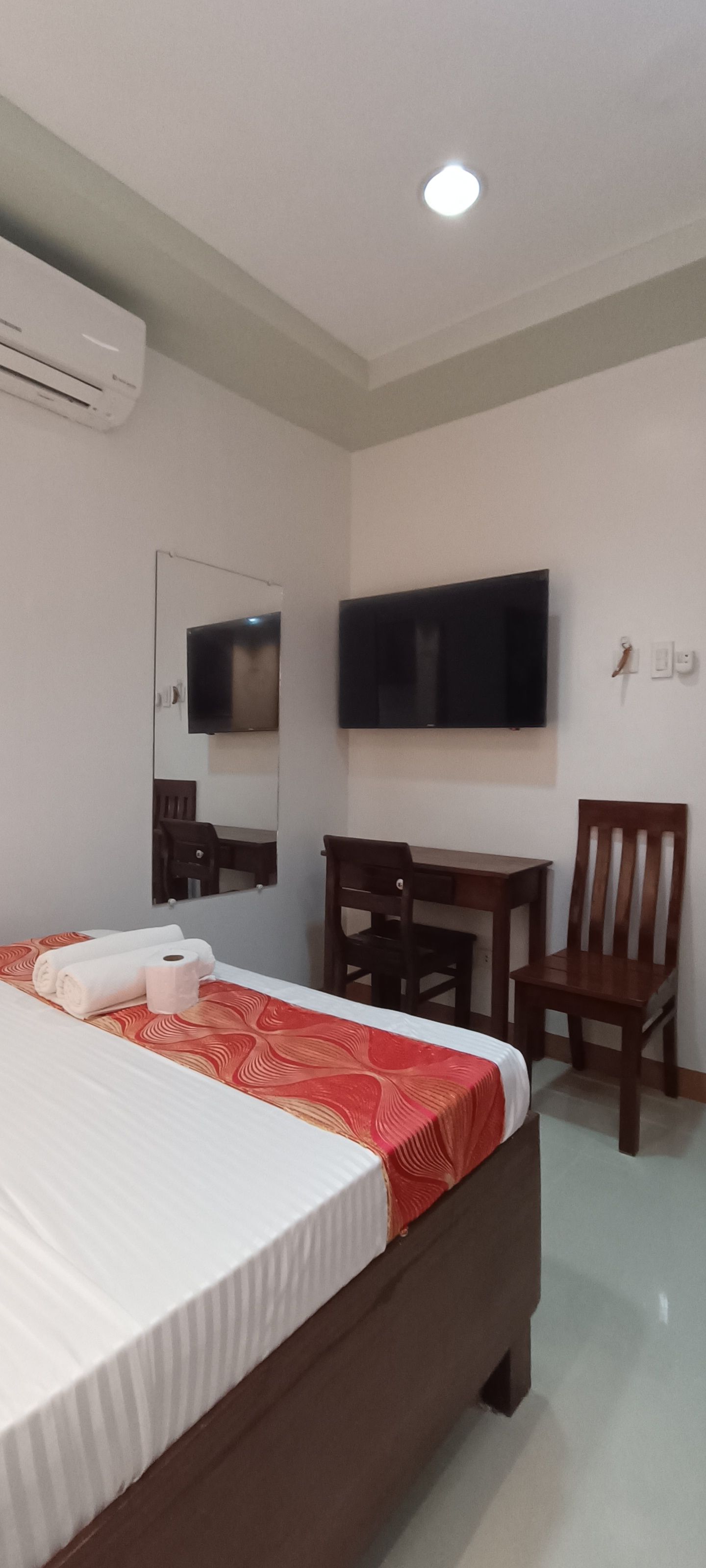 A hotel room with a bed , chair , desk and television.