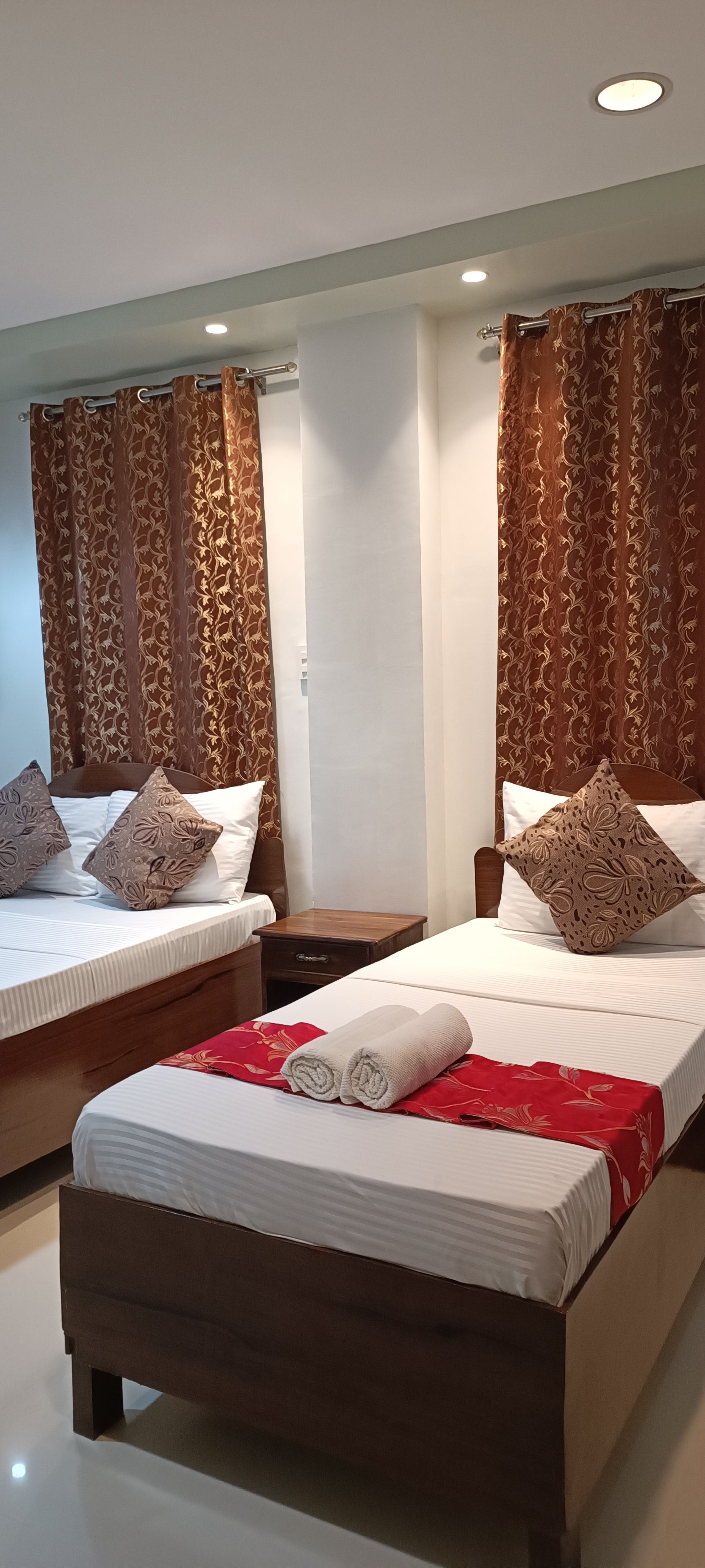 A hotel room with two beds and a nightstand.