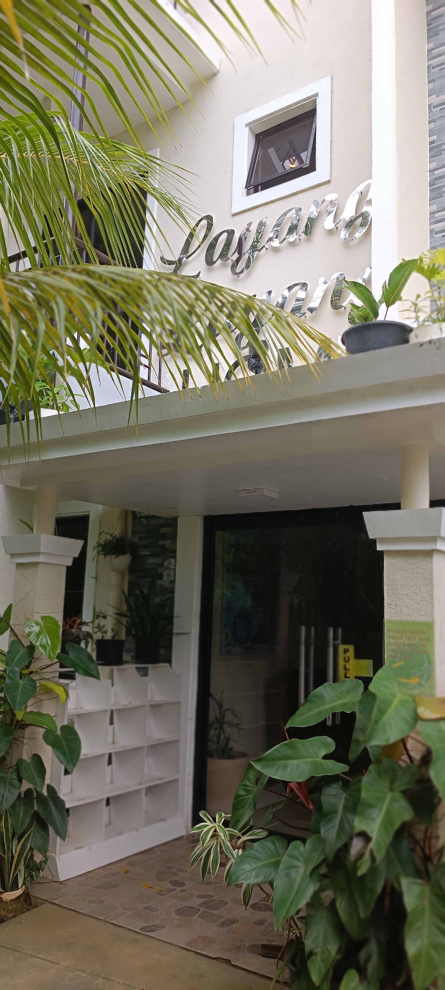 A white building with a lot of plants in front of it.